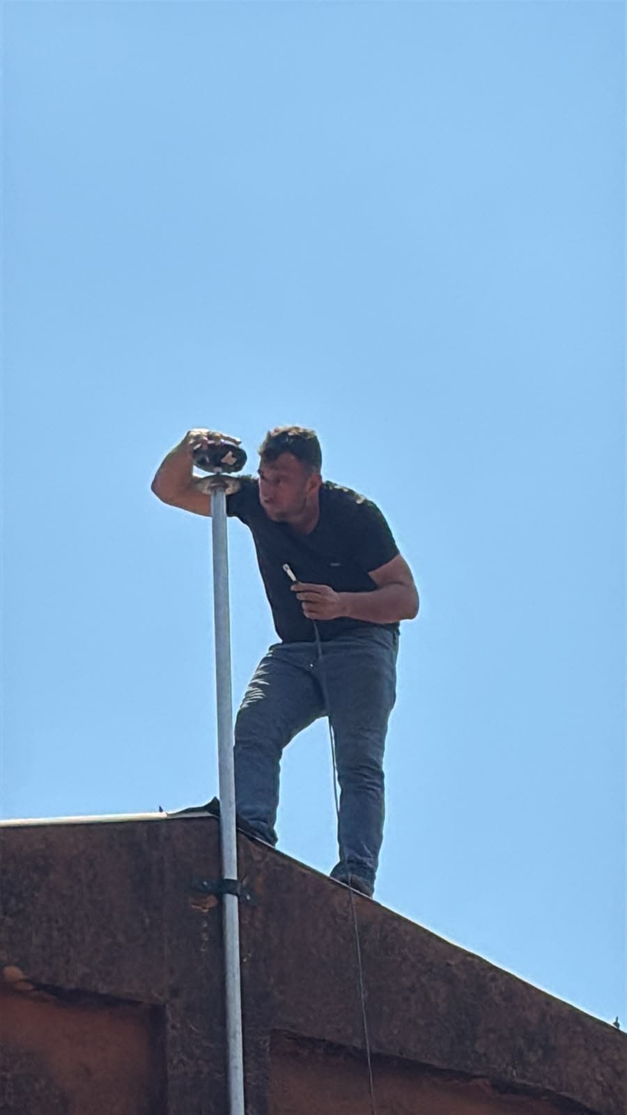 Technician mounting an antenna on a roof